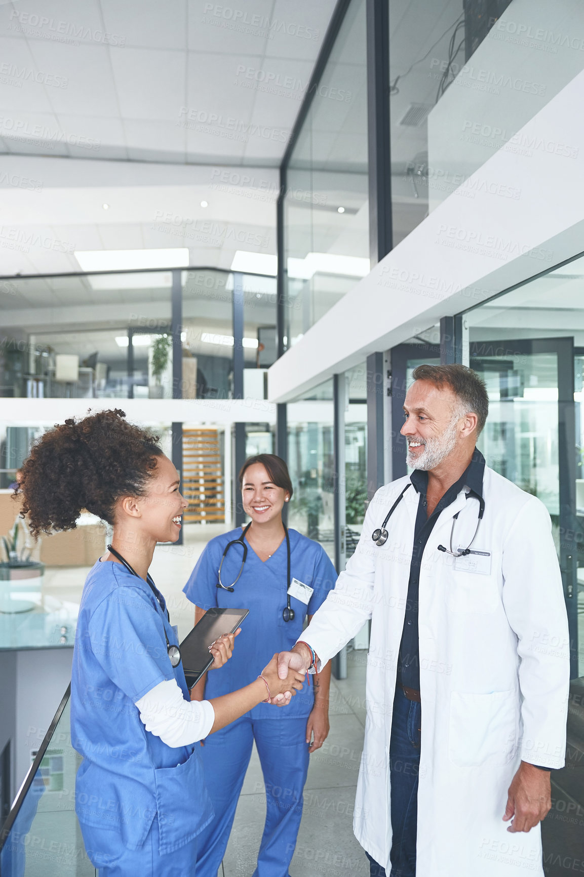 Buy stock photo Cropped shot of a handsome mature doctor standing and shaking a nurse's hand in the clinic