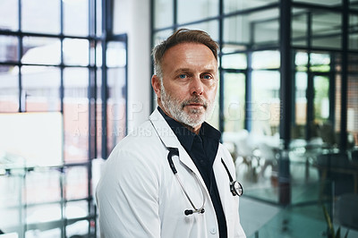Buy stock photo Cropped portrait of a handsome mature doctor standing in the clinic during the day