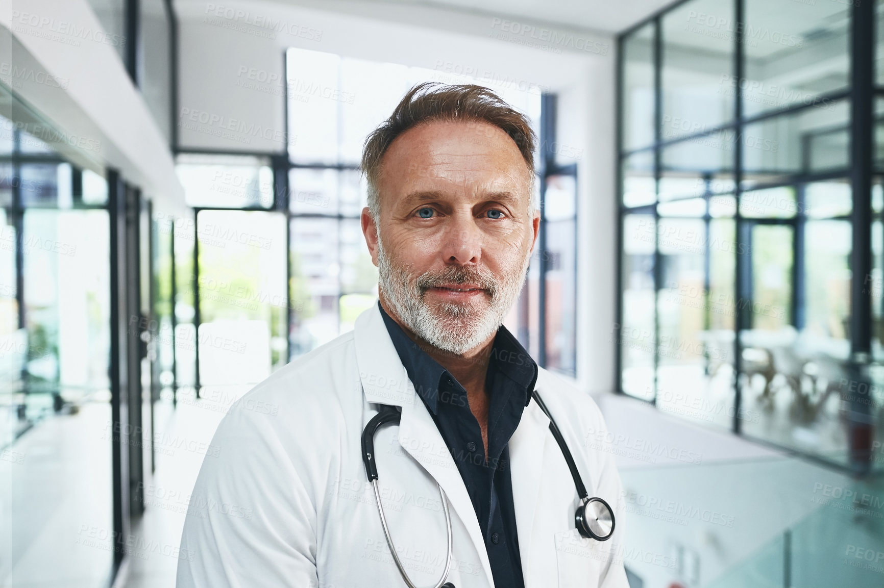 Buy stock photo Cropped portrait of a handsome mature doctor standing in the clinic during the day