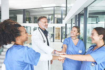 Buy stock photo Cropped shot of a diverse group of healthcare professionals standing huddled together with their hands in the middle