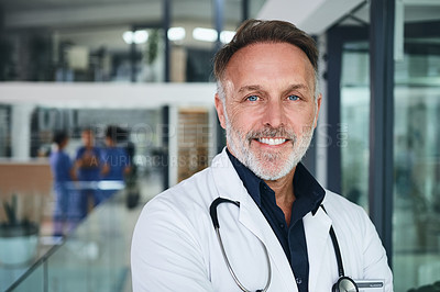 Buy stock photo Cropped portrait of a handsome mature doctor standing in the clinic during the day