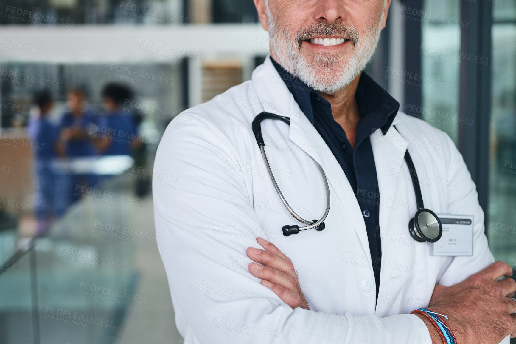 Buy stock photo Cropped shot of an unrecognizable doctor standing with his arms folded in the clinic during the day