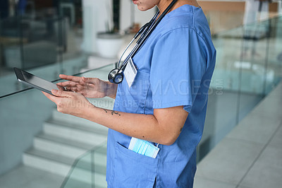 Buy stock photo Cropped shot of an unrecognizable young nurse standing and using a digital tablet in the clinic