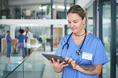 Buy stock photo Cropped shot of an attractive young nurse standing and using a digital tablet in the clinic