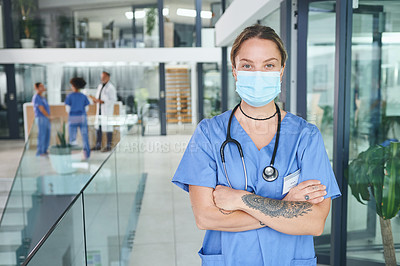 Buy stock photo Cropped portrait of an attractive young nurse wearing a face mask and standing in the clinic with her arms folded