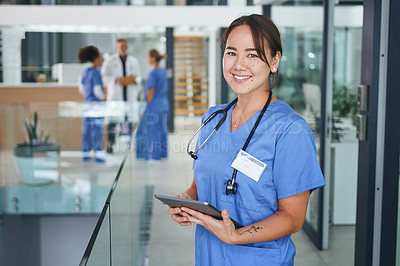 Buy stock photo Cropped portrait of an attractive young nurse standing and using a digital tablet in the clinic