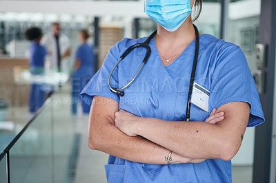 Buy stock photo Cropped shot of an unrecognizable nurse wearing a face mask and standing in the clinic with her arms folded