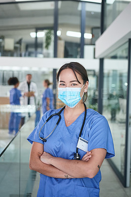 Buy stock photo Cropped portrait of an attractive young nurse wearing a face mask and standing in the clinic with her arms folded