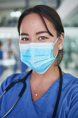 Buy stock photo Cropped portrait of an attractive young nurse wearing a face mask and standing alone in the clinic