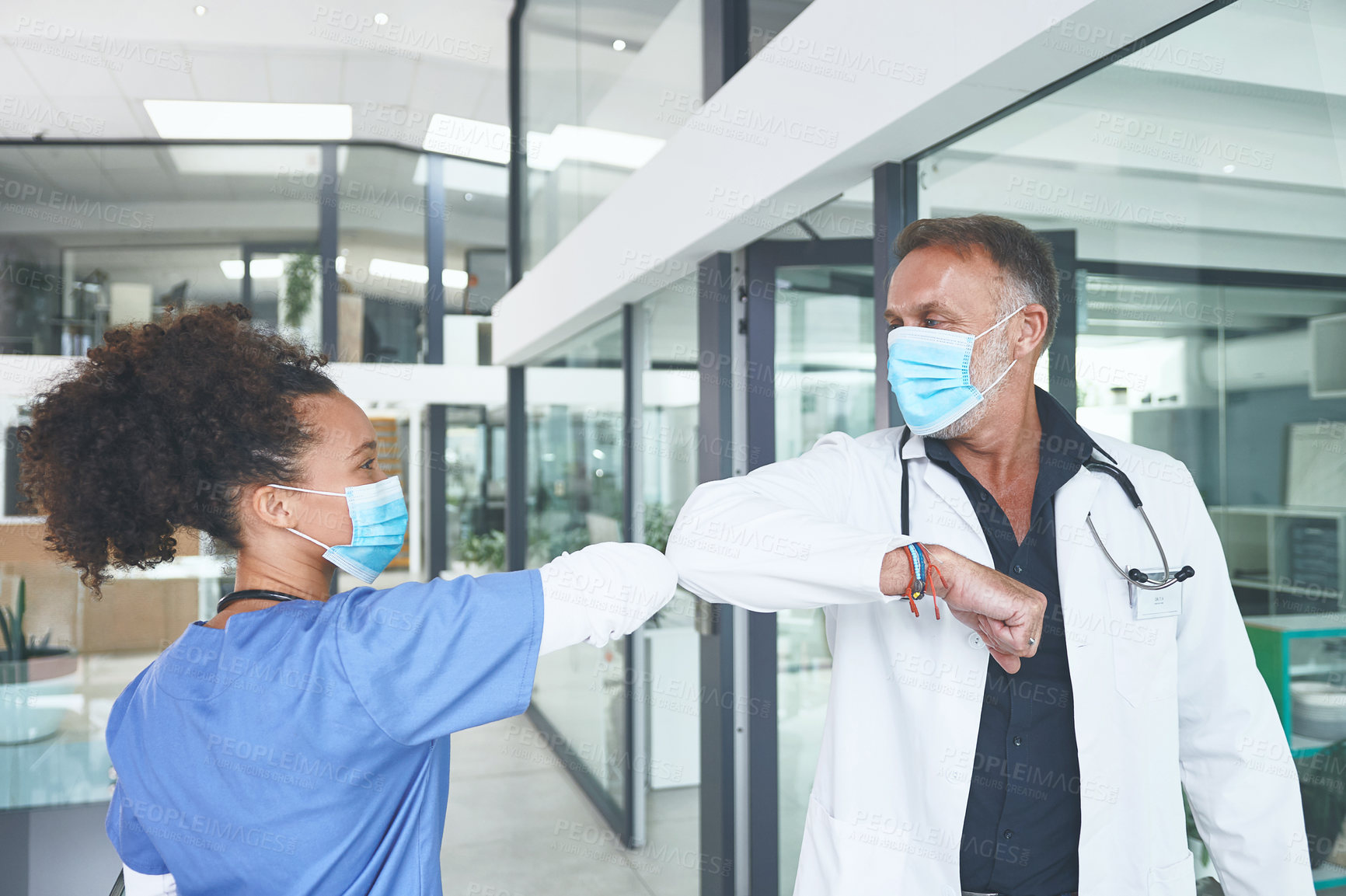 Buy stock photo Cropped shot of a handsome mature doctor standing and elbow bumping his nurse as a greeting in the clinic