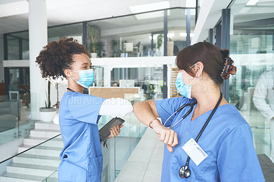 Buy stock photo Cropped shot of an attractive young nurse standing and elbow bumping a coworker as a greeting in the clinic