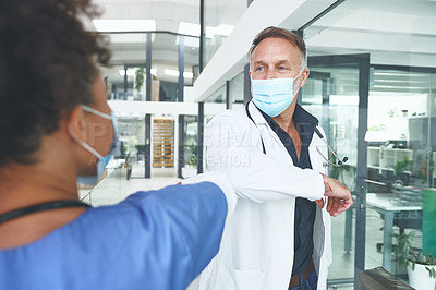 Buy stock photo Cropped shot of a handsome mature doctor standing and elbow bumping his nurse as a greeting in the clinic