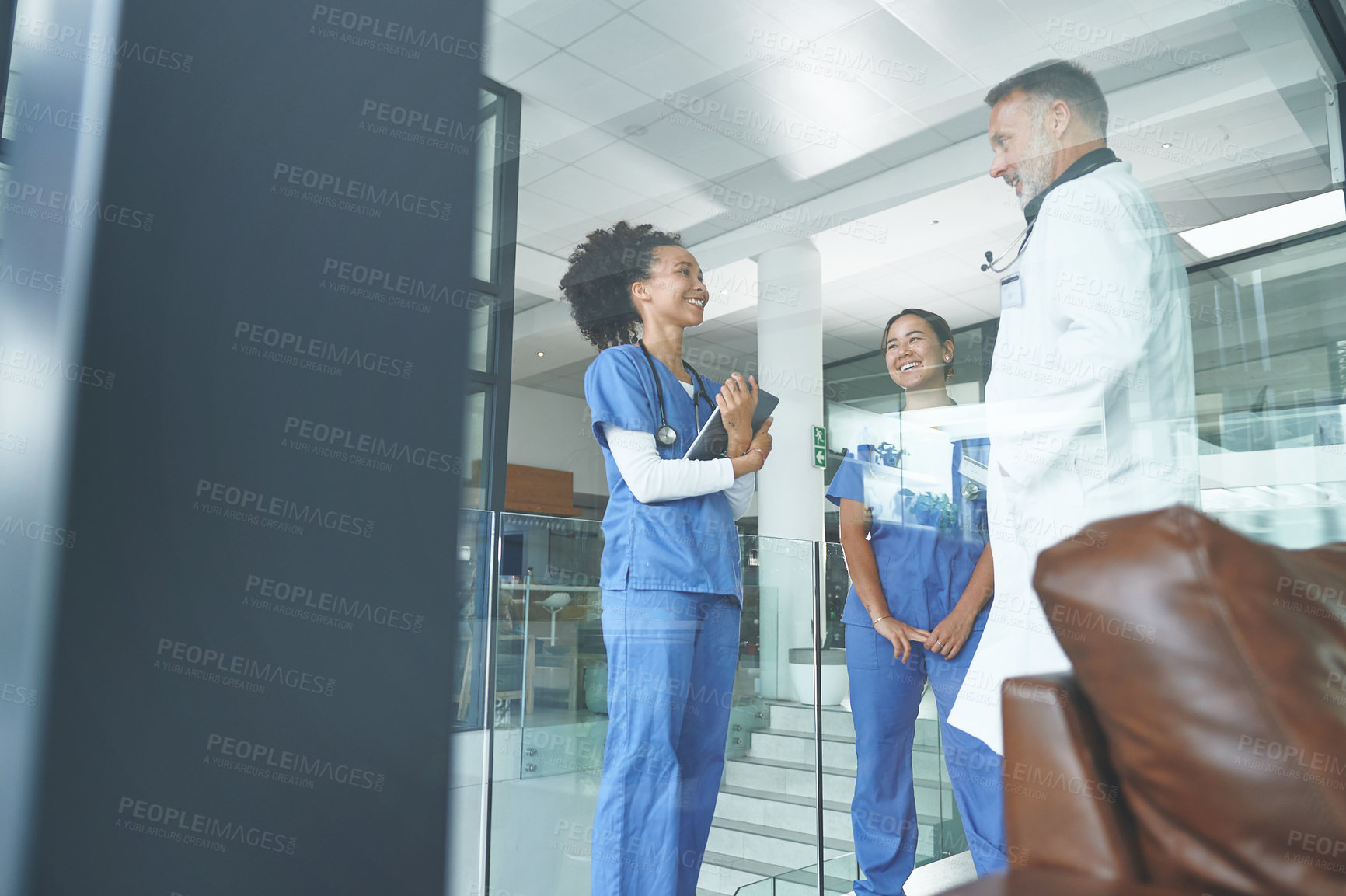 Buy stock photo Cropped shot of an attractive young nurse standing with coworkers and having a discussion in the clinic