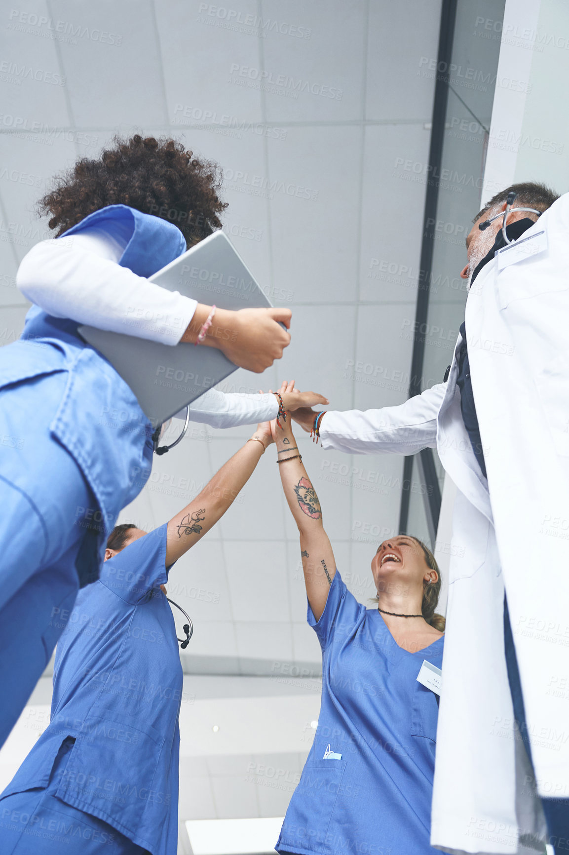 Buy stock photo Low angle shot of a diverse group of healthcare professionals standing and giving each other a high five