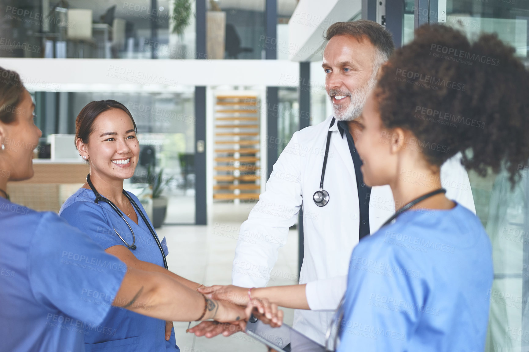 Buy stock photo Cropped shot of a diverse group of healthcare professionals standing huddled together with their hands piled in the middle