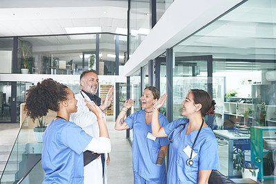 Buy stock photo Cropped shot of a diverse group of healthcare professionals standing and giving each other a high five