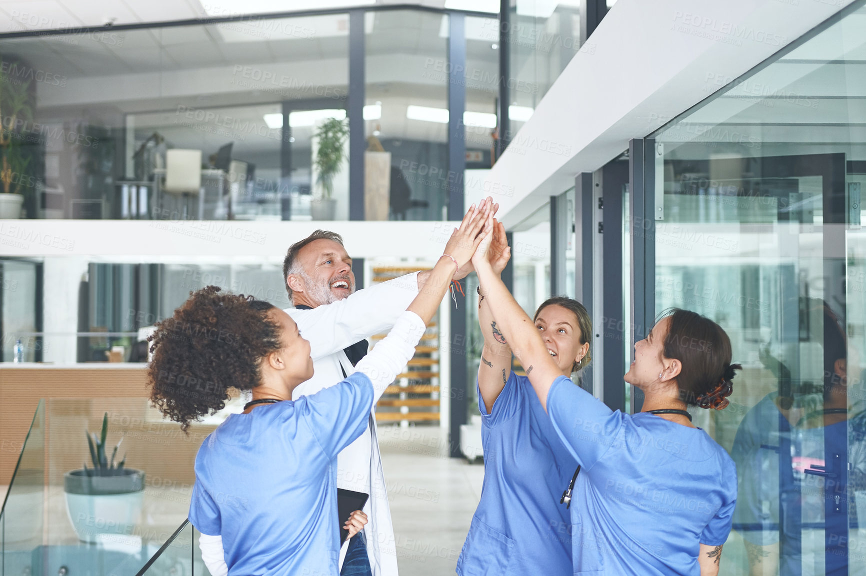 Buy stock photo Cropped shot of a diverse group of healthcare professionals standing and giving each other a high five
