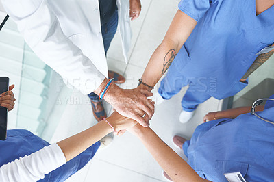 Buy stock photo High angle shot of an unrecognizable group of healthcare professionals standing huddled together with their hands piled in the middle