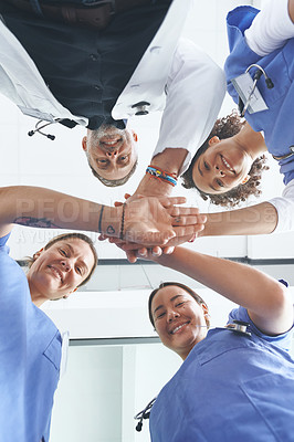 Buy stock photo Low angle portrait of a diverse group of healthcare professionals standing huddled together with their hands piled in the middle