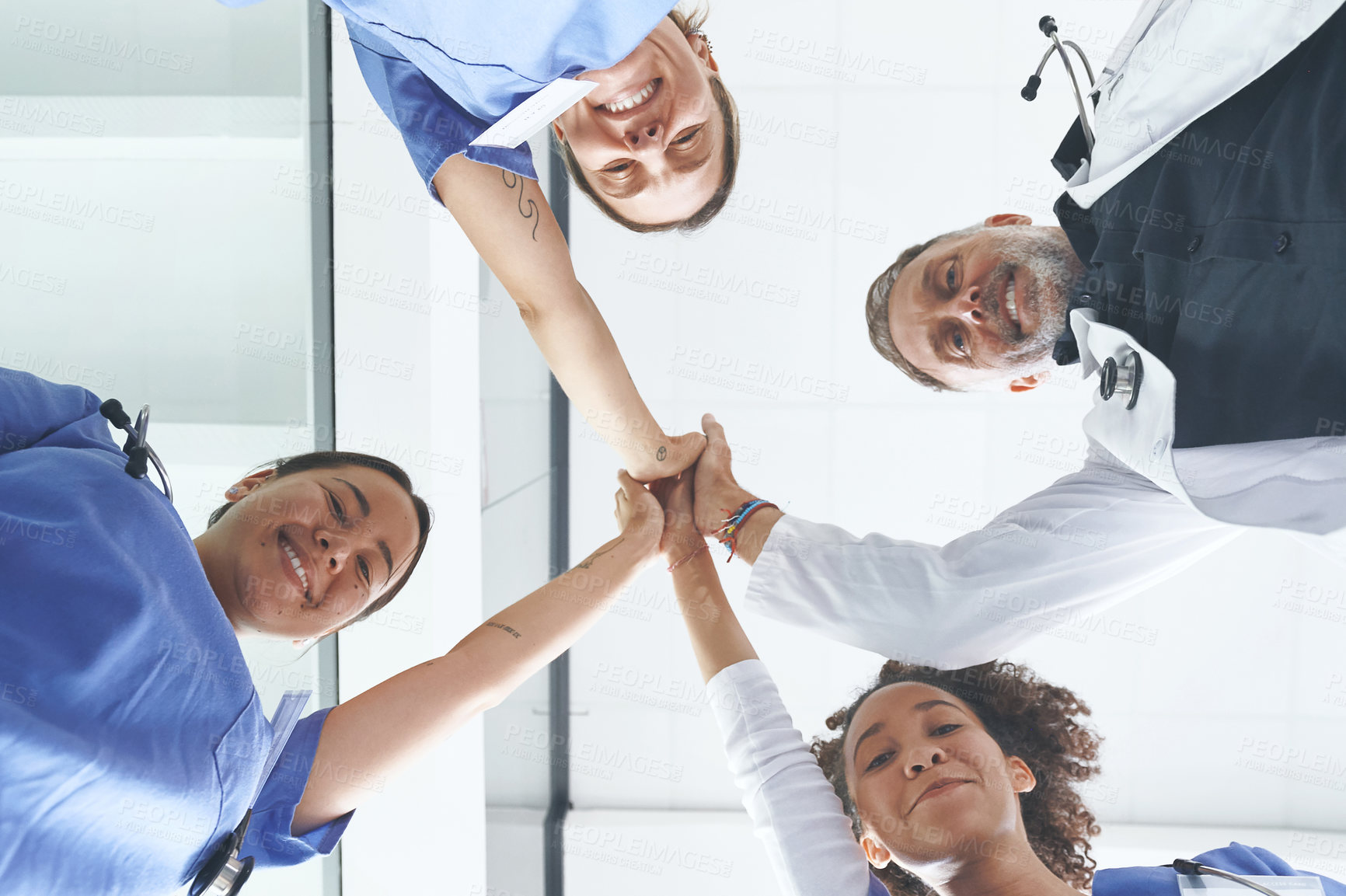 Buy stock photo Low angle portrait of a diverse group of healthcare professionals standing and giving each other a high five