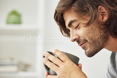 Buy stock photo Shot of young man drinking a cup of coffee happily.