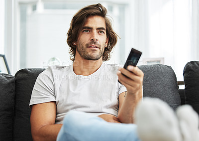 Buy stock photo Shot of man watching TV on his sofa