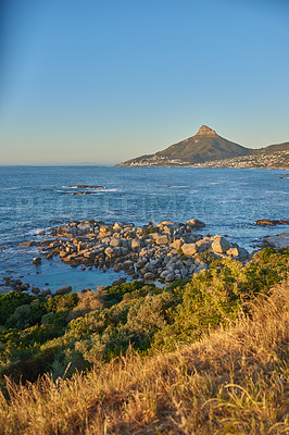 Buy stock photo Landscape view of sea water, mountains and a blue sky with copy space of Lions Head in Cape Town, South Africa. Calm, serene and tranquil ocean and relaxing nature scenery with shrubs and brown grass