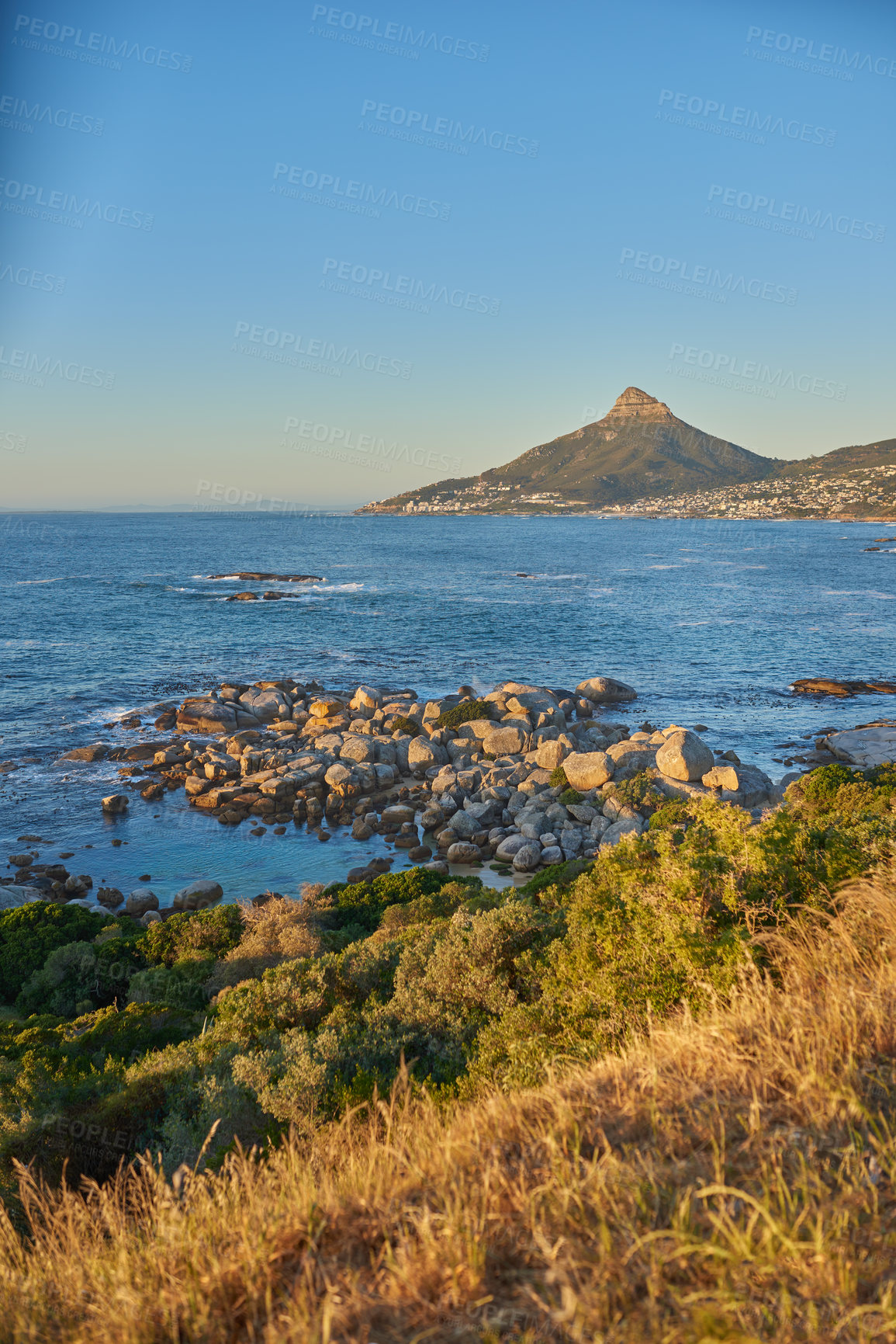 Buy stock photo Landscape view of sea water, mountains and a blue sky with copy space of Lions Head in Cape Town, South Africa. Calm, serene and tranquil ocean and relaxing nature scenery with shrubs and brown grass