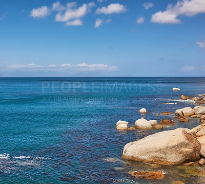 Buy stock photo The landscape of a tropical holiday destination. Beautiful rocky beach with a cloudy blue sky background on a summer day with copy space. Seascape with large rocks and calm water during spring. 