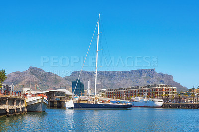 Buy stock photo Sailboats docked at a harbor with Table Mountain in the background against blue sky with copy space. Scenic landscape of waterfront port at a marina dockyard. Nautical vessels for travel and tourism
