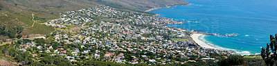 Buy stock photo Panoramic landscape of a large city on the coast from above. Beautiful scenic and aerial view of a popular tourist town or residential area with greenery and the ocean in nature during summer