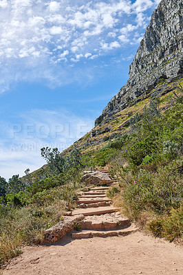 Buy stock photo Beautiful view of a mountain trail in a natural environment against a cloudy blue sky in summer. Empty and remote path for walking in a valley or national park with trees, greenery, and vegetation