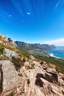 Buy stock photo Sky divers paragliding over rocky mountain trail for tourists seeking a thrill is a great activity to explore when on holiday or vacation. Nature and ocean, blue sky background with copy space