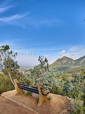 Buy stock photo Bench with a beautiful view of Table Mountain and sea against a clear blue sky background with copy space. Relaxing spot for a peaceful break to enjoy the scenic landscape after a hike up a cliff