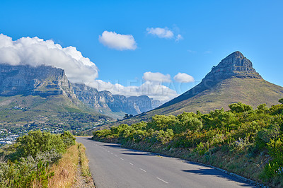 Buy stock photo Panoramic and scenic view of an empty road in the countryside with mountains and greenery in summer. Beautiful landscape view of a quiet street surrounded by natural landmarks against a blue sky