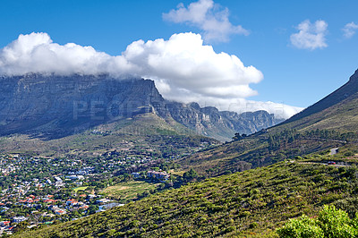 Buy stock photo Panorama of a city near mountains in South Africa. Landscape of Cape Town suburbs beneath Table Mountain and a cloudy blue sky. Beautiful greenery and scenic nature near a rural town with copy space.