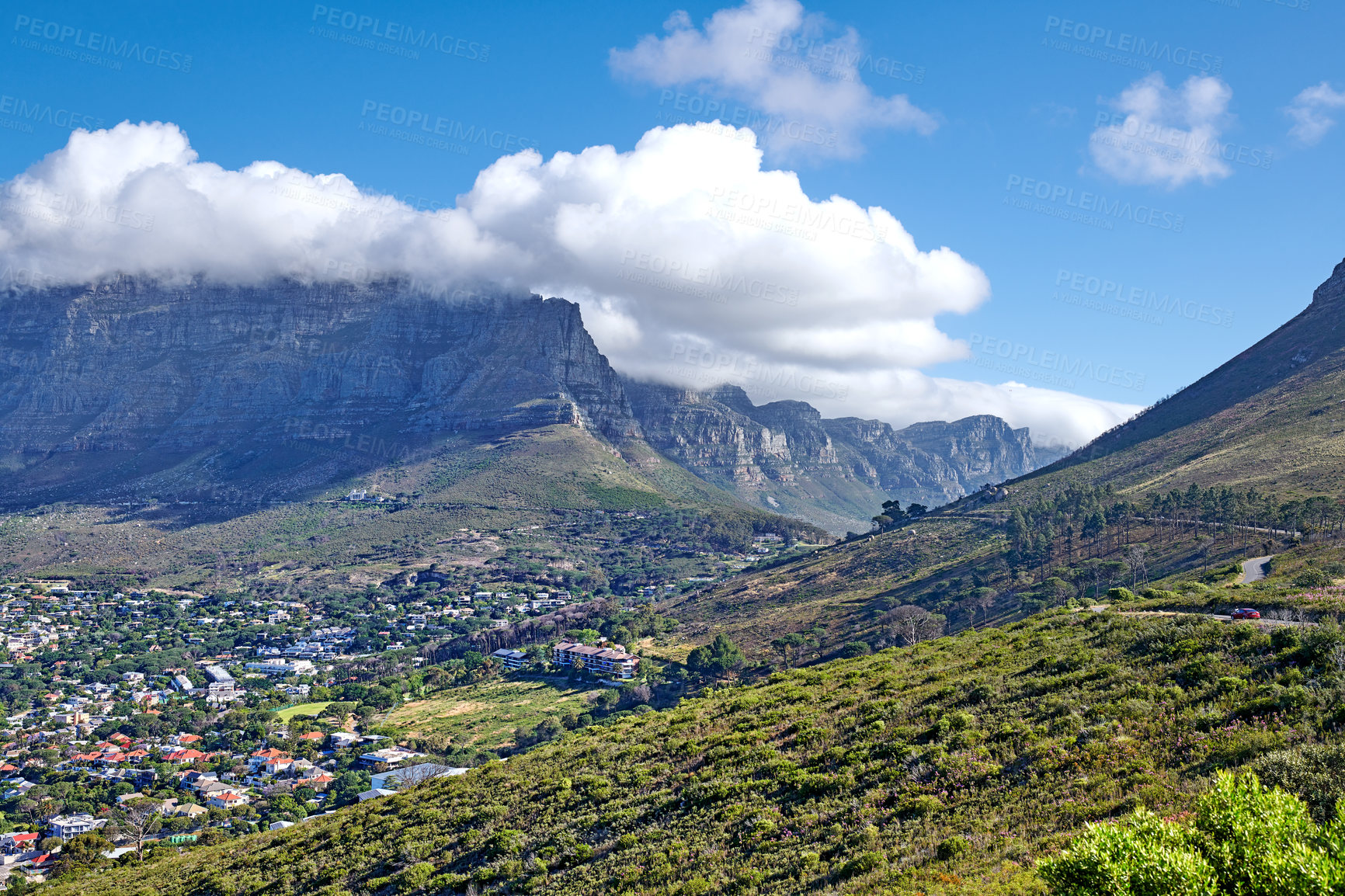 Buy stock photo Panorama of a city near mountains in South Africa. Landscape of Cape Town suburbs beneath Table Mountain and a cloudy blue sky. Beautiful greenery and scenic nature near a rural town with copy space.