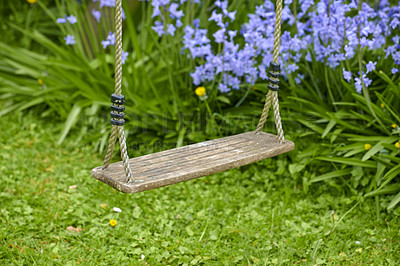 Buy stock photo Old wooden swing in a garden with blue flowers and moss growing in backyard. Peaceful scene of a forgotten playground with lush greenery and wild bluebells on overgrown lawn in spring with copy space