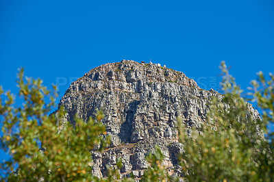 Buy stock photo Landscape view of mountain, copy space and blue sky background from lush, green botanical garden or national park. Low angle of rough, rocky or dangerous terrain in remote location overseas or abroad