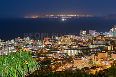 Buy stock photo Urban city lights against a midnight sky with copy space. Skyline with colorful lighting and the open ocean on the horizon. Modern architectural buildings, vacation hotels in an urban city