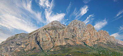 Buy stock photo Landscape view of a mountainside with copy space and blue sky background from a lush, green botanical garden or national park. Low angle of rough, rocky, or dangerous terrain in a remote location