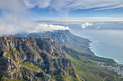 Buy stock photo Aerial view of mountain and calm ocean with a blue cloudy sky background and copy space. Stunning nature landscape of the sea and horizon from Table Mountain with beautiful greenery in Cape Town