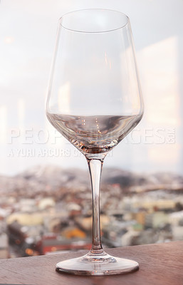 Buy stock photo Close up still life of a wine glass on a window sill overlooking a city background. Empty, fresh and  clean glass standing  on a wooden surface