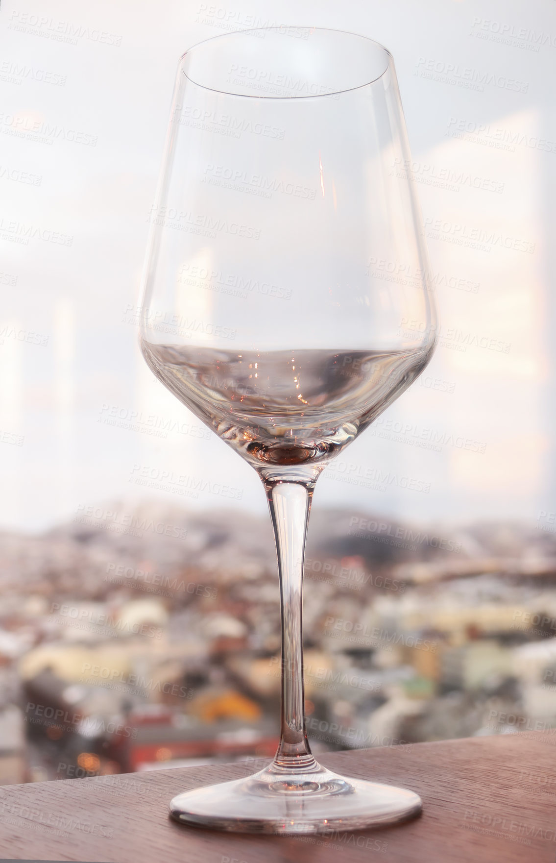 Buy stock photo Close up still life of a wine glass on a window sill overlooking a city background. Empty, fresh and  clean glass standing  on a wooden surface