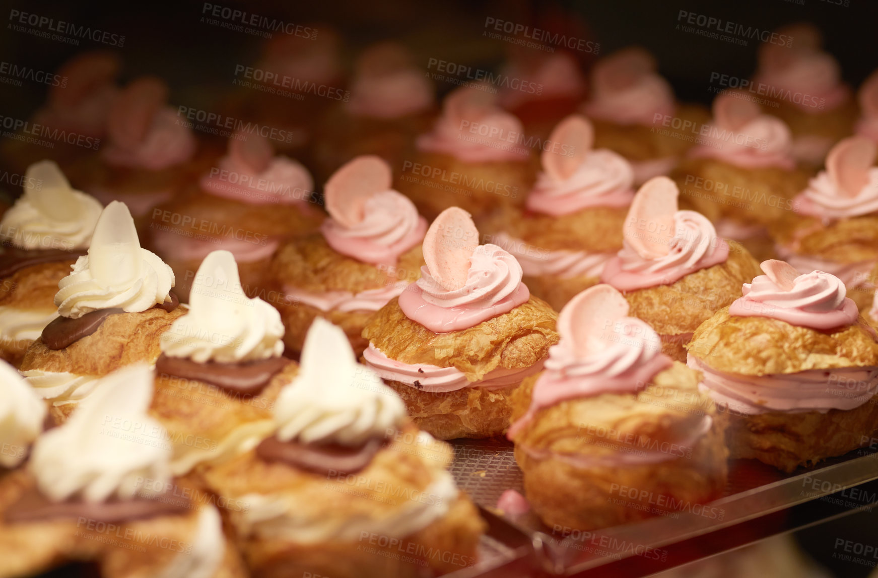 Buy stock photo Closeup of cakes and baked goods in an oven at a bakery. Delicious and fresh pastries being prepared and ready to sell at a cake shop. Light and yummy snacks for a party or event on a shelf at a cafe