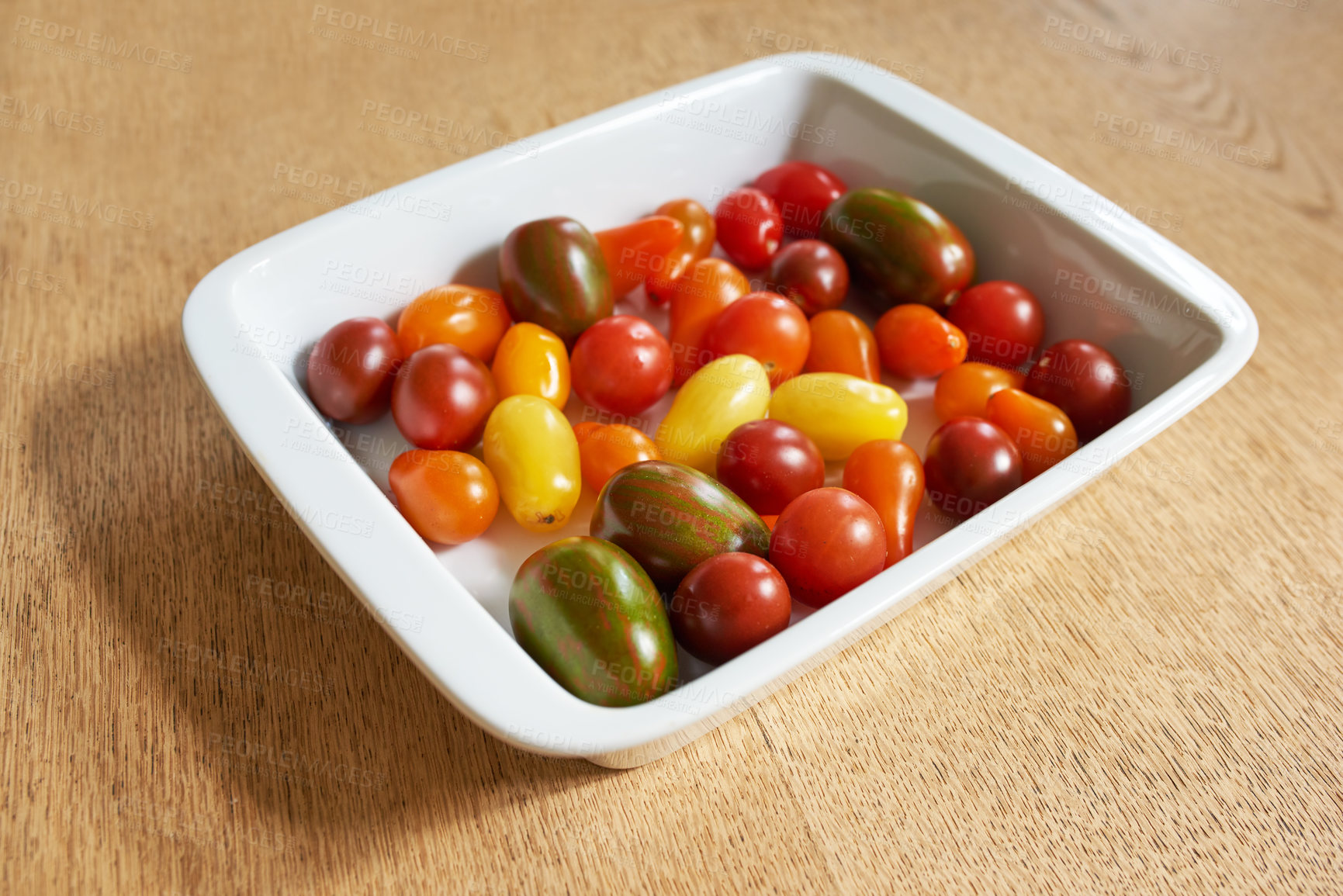 Buy stock photo Closeup of roma or cherry tomatoes in a glass bowl served on a wooden table for diet, healthy salads and nutrition. Fresh, organic fruit farmed in home garden or agriculture farm