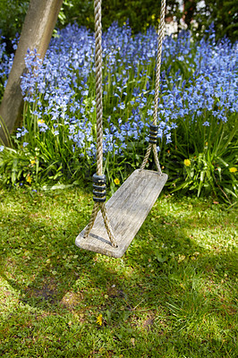 Buy stock photo Fun garden swing for children to relax, enjoy and play on a weekend or break with common bluebell flowers growing in background. Homemade wood and rope playset in a home backyard or park playground