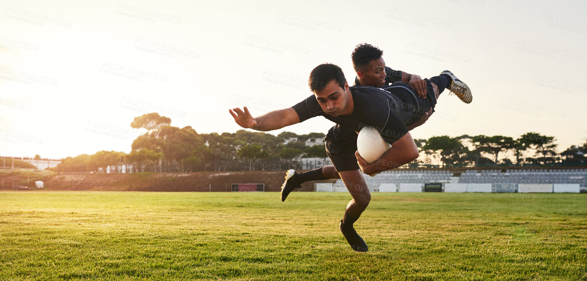 Buy stock photo Full length shot of two handsome sportsmen playing rugby during a training session during the day