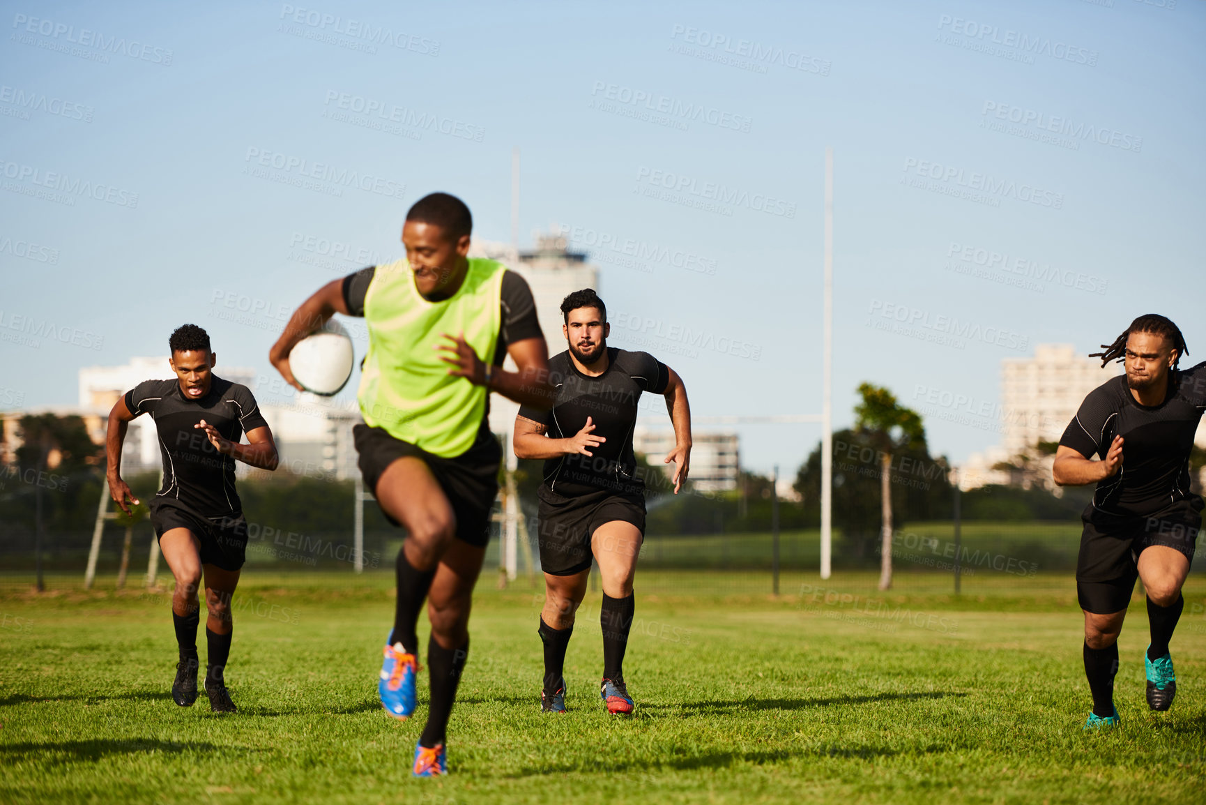 Buy stock photo Full length shot of a diverse group of sportsmen playing a game of rugby during the day