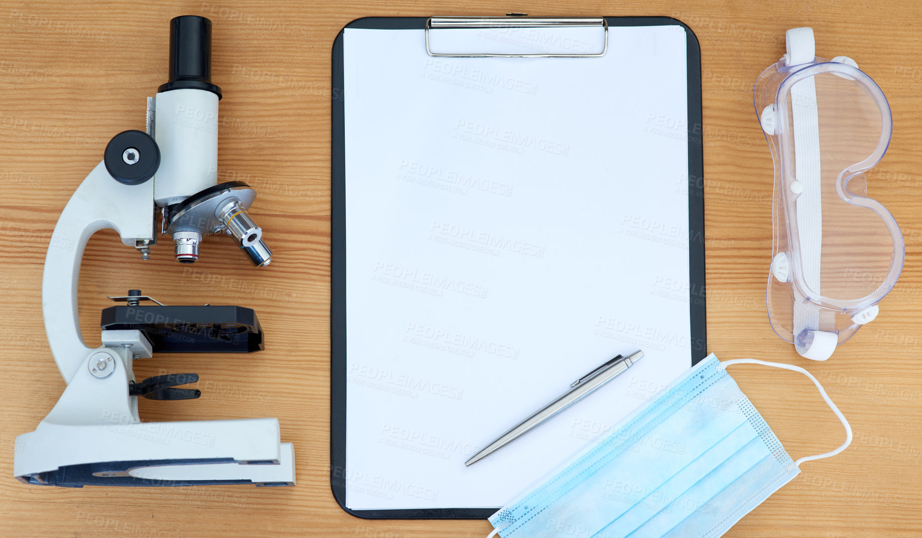 Buy stock photo High angle shot of a microscope, clipboard, pen, protective glasses and face mask on a table